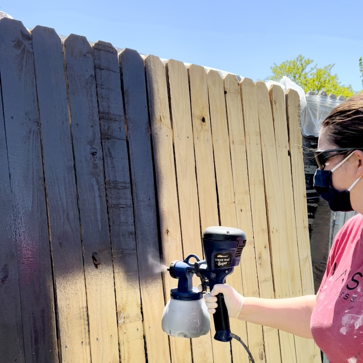 spraying stain on fence